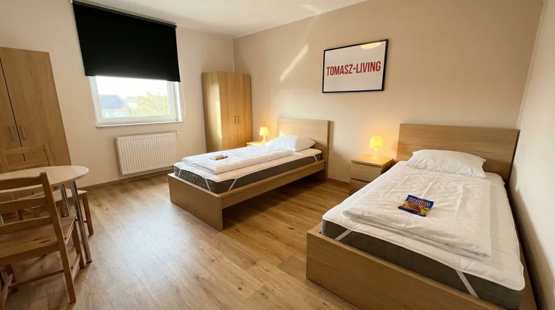 Zweibettzimmer mit Tisch und zwei Stühlen am Fenster