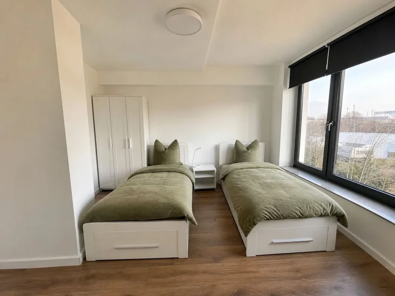 Zweibettzimmer mit getrennten Einzelbetten und breiter Fensterfront