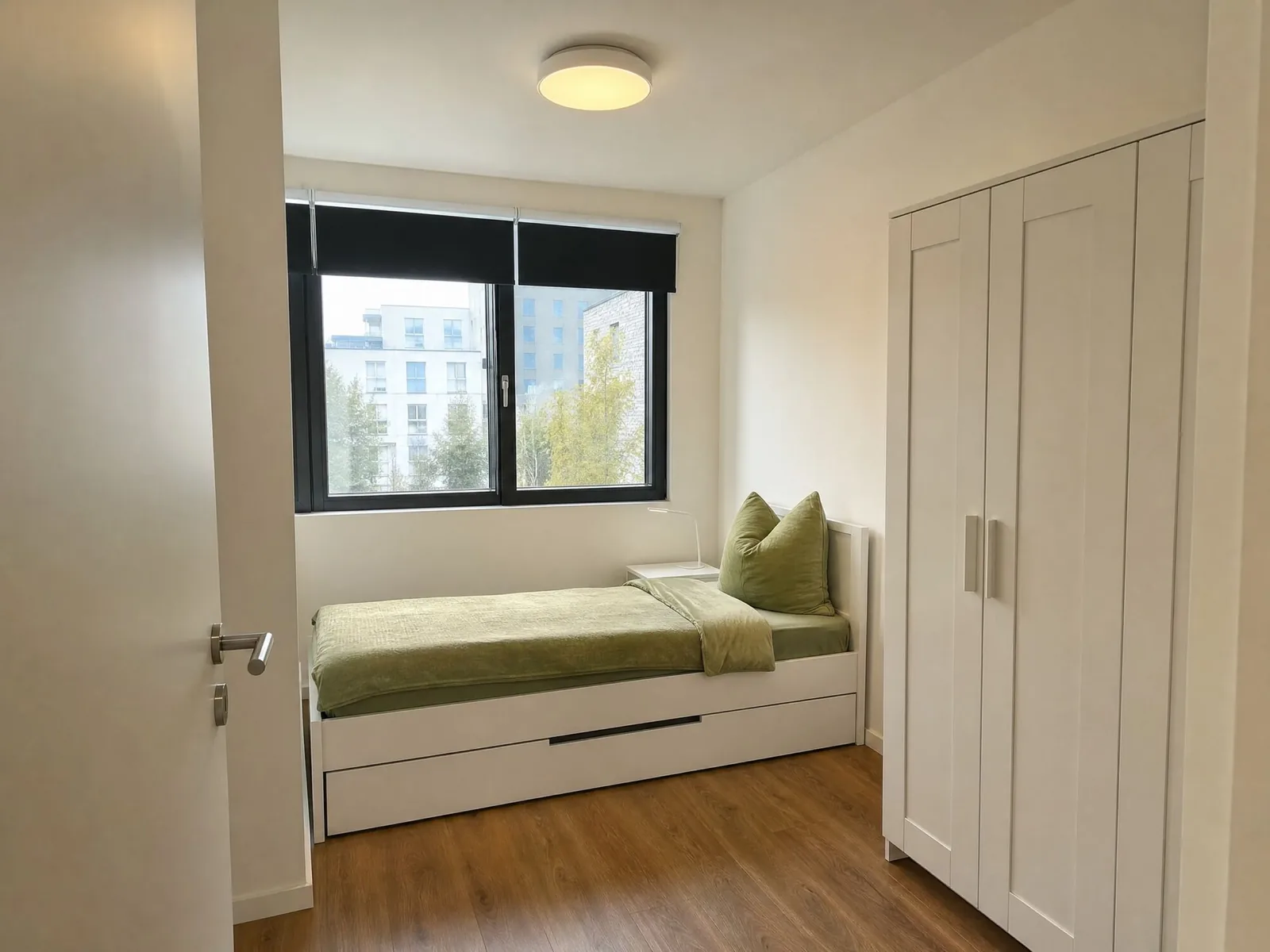 Einzelzimmer mit Bett, großem Kleiderschrank und Fenster