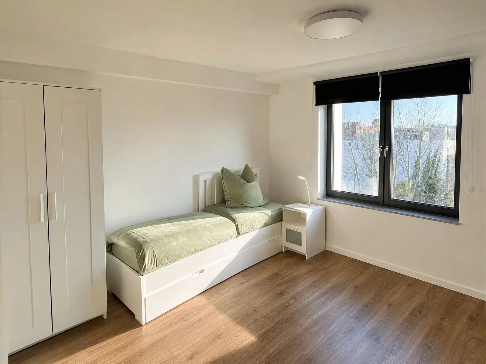Helles Einzelzimmer mit Bett, Kleiderschrank und Fenster