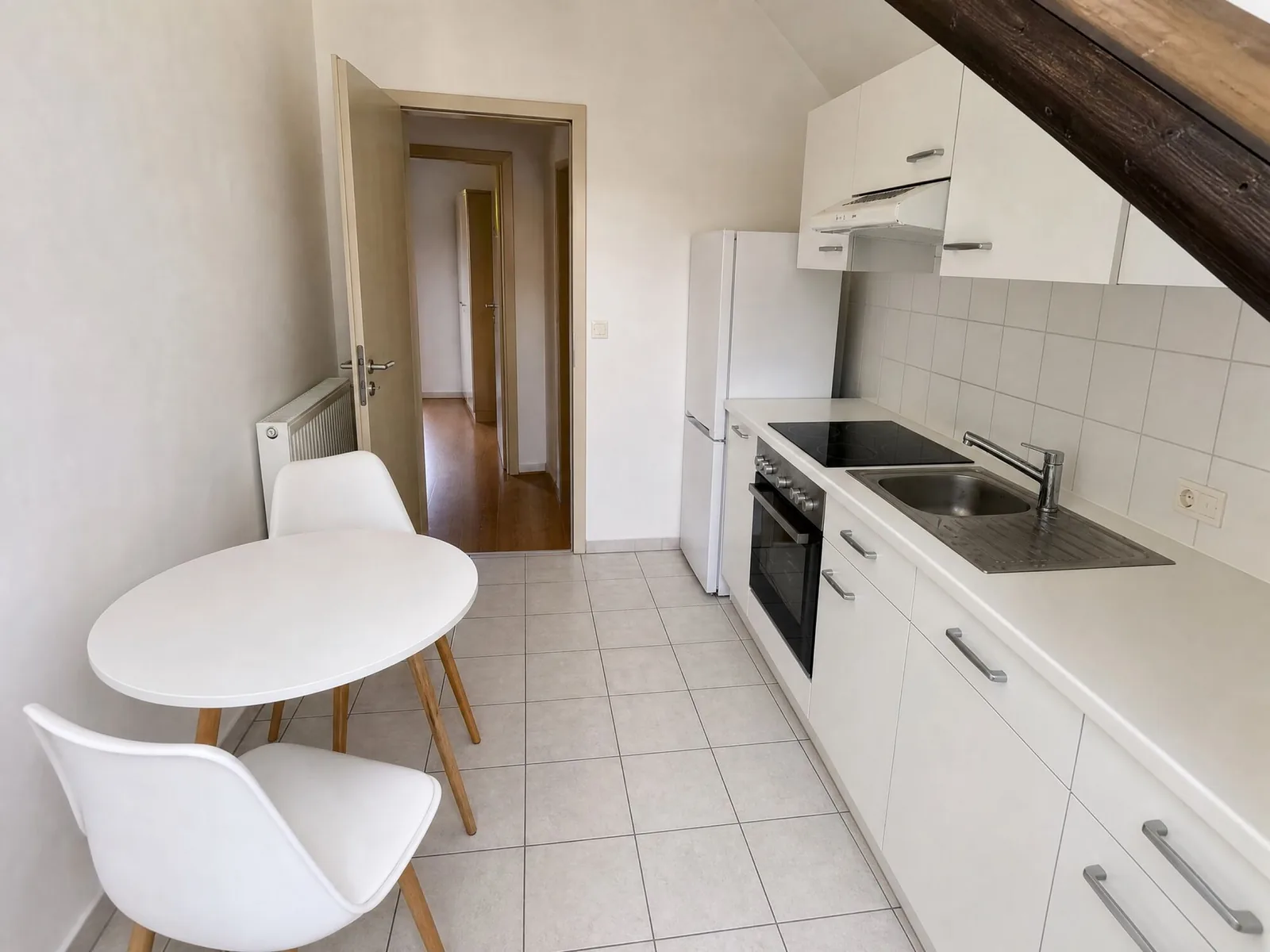 Schmale Küchenzeile mit Backofen, Spüle und rundem Tisch