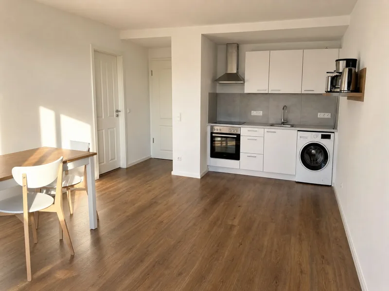 Helle Wohnküche mit Backofen, Waschmaschine und Esstisch